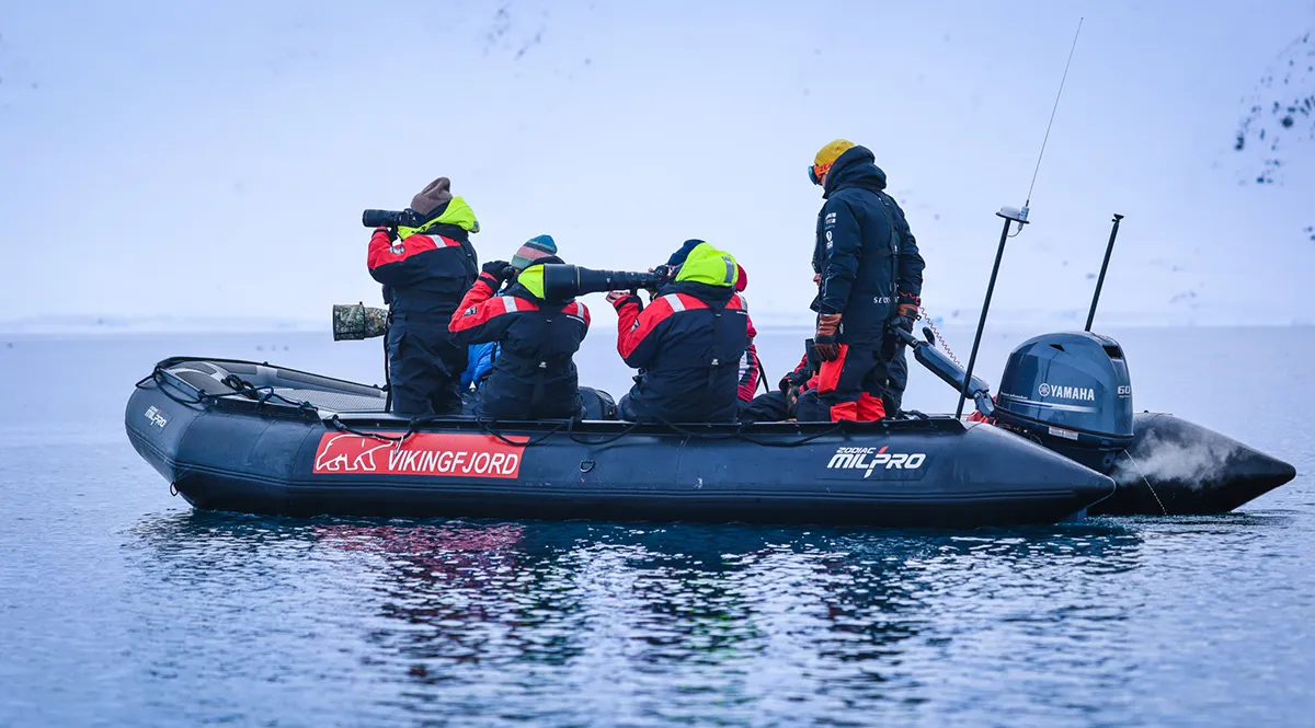 Team in Zodiac boat photographing wildlife during Vikingfjord expedition charter in Arctic waters