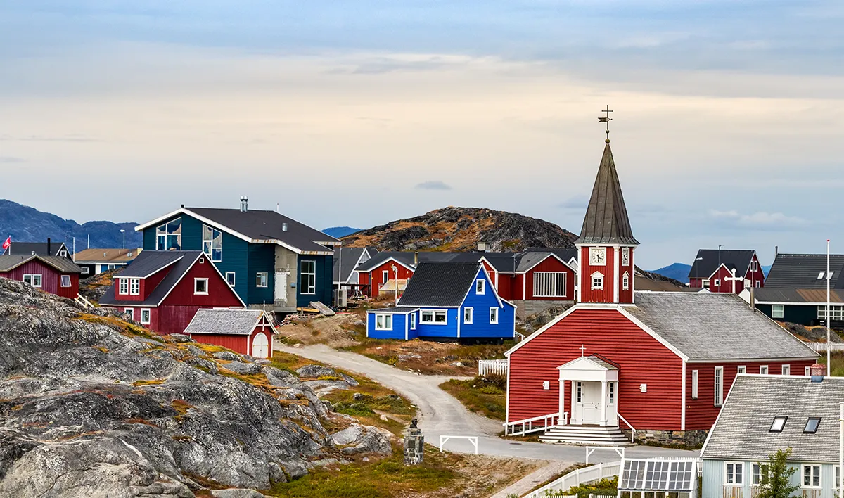 Traditional colourful houses and church in a Greenland coastal village seen during a Vikingfjord expedition cruise