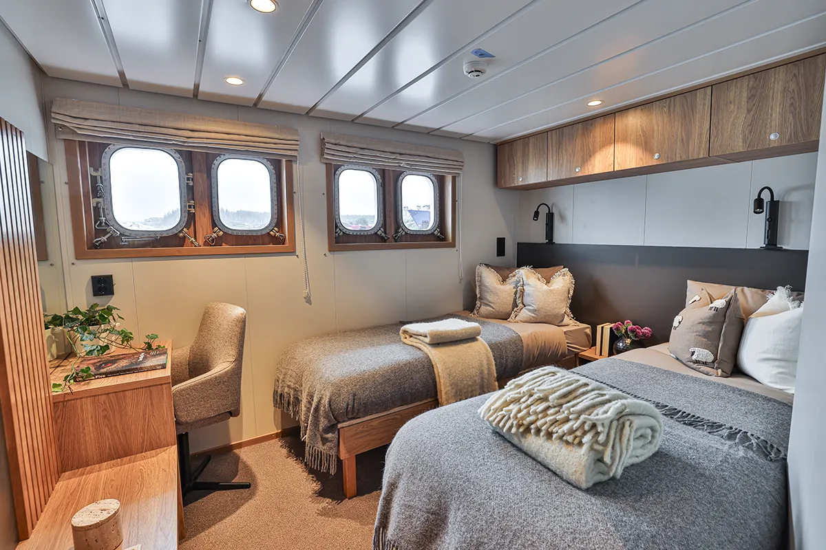 Interior of a twin cabin aboard Vikingfjord expedition vessel with two beds and sea view window